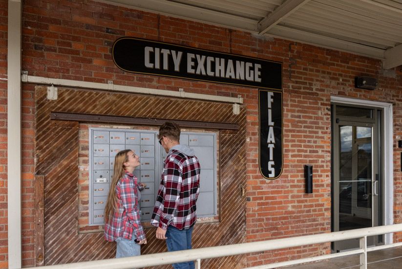 People smiling at each other in front of the City Exchange Building in Harrisonburg. Ready to be a great neighbor!